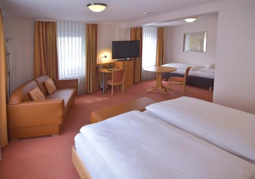 a hotel room with a bed and a couch and a television at Hotel - Restaurant Hirsch in Heimsheim