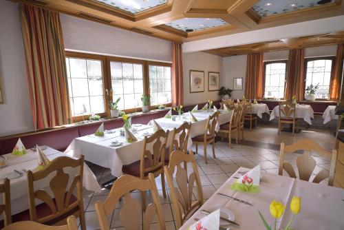 un restaurant avec des tables blanches, des chaises et des fenêtres dans l'établissement Hotel - Restaurant Hirsch, à Heimsheim