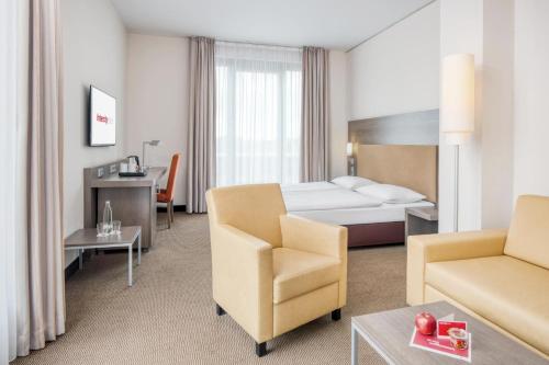 ein Hotelzimmer mit einem Bett, einem Sofa und einem Stuhl in der Unterkunft IntercityHotel Dresden in Dresden