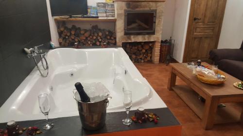 una gran bañera blanca en la sala de estar con copas de vino en La Escapada Cuenca, en Pajaroncillo