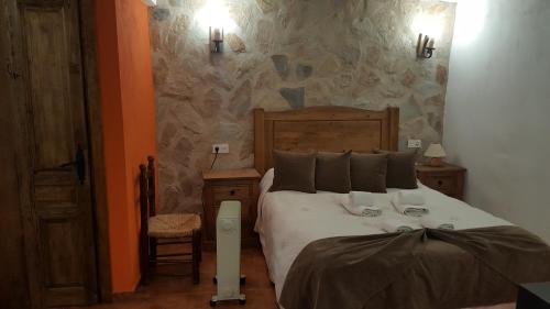 1 dormitorio con cama y pared de piedra en La Escapada Cuenca, en Pajaroncillo