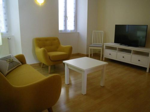 ein Wohnzimmer mit einem TV, einem Tisch und Stühlen in der Unterkunft La Galerie Privée in Pontcharra