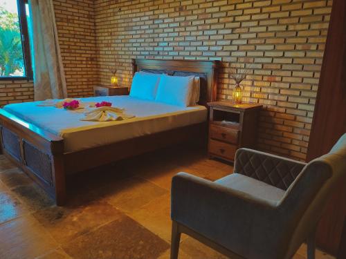 a bedroom with a large bed with a chair and a chair at Refúgios Parajuru - Villa Cristiano in Parajuru