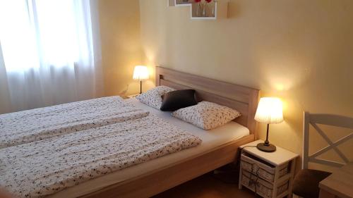 a bedroom with a bed with two pillows and two lamps at Apartman Lotos in Mikulov