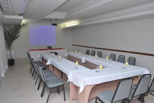 a conference room with tables and chairs and a screen at Hotel Barramares in Recife