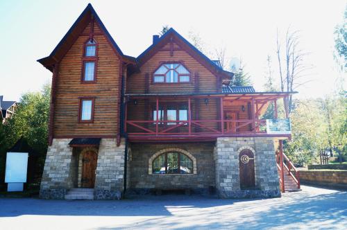 een groot houten huis met een veranda bovenop bij Норіс in Myhove