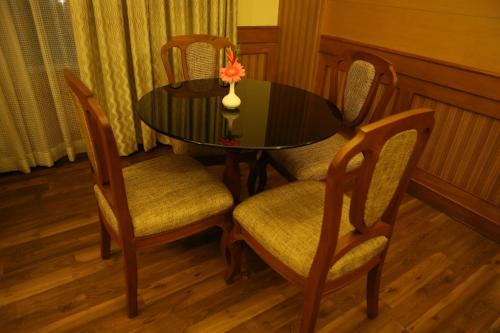 a dining room table and chairs with a vase on it at Hotel Airlink Castle in Nedumbassery