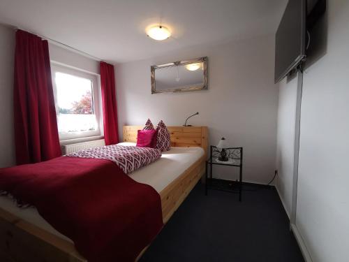a bedroom with a bed and a window with red curtains at Hildfelder Stübchen in Winterberg