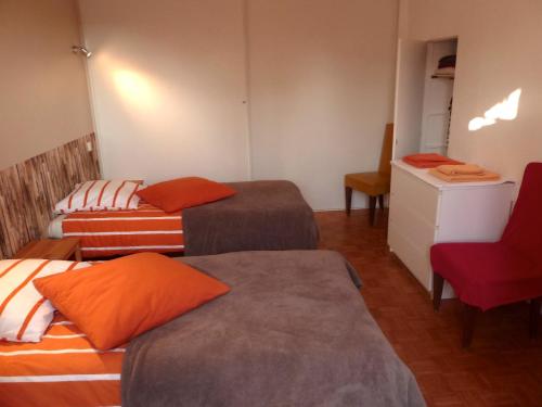 Zimmer mit 3 Betten und einem roten Stuhl in der Unterkunft La Longère aux Volets Rouges, Meublé Tourisme 2 étoiles in Maillebois