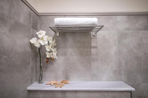 a vase of flowers on a shelf in a bathroom at Levkosh Apartments at Lefkada's Heart in Lefkada Town