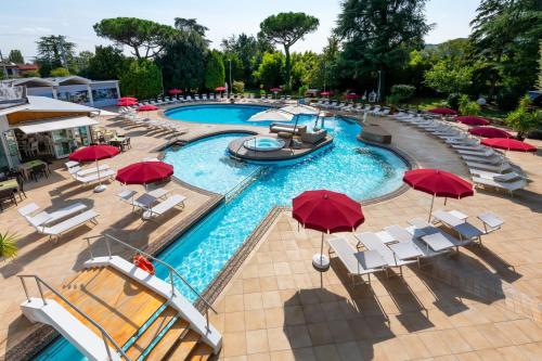 an image of a pool with red umbrellas and chairs at Hotel Mioni Royal San in Montegrotto Terme