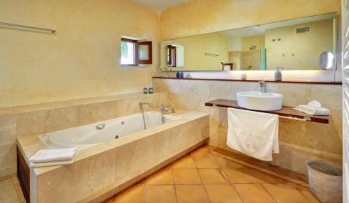 a bathroom with a tub and a sink and a mirror at Villa Golf D'or in Portocolom