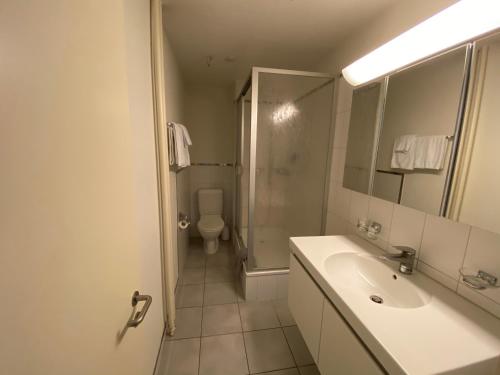 a bathroom with a sink, mirror, and bathtub at Hotel Bramen in Kloten