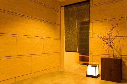 a room with wooden walls and a vase with a plant at Sakura Terrace in Kyoto