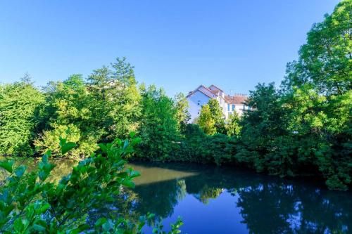 ein Fluss mit Bäumen und ein Haus im Hintergrund in der Unterkunft Hotel Strasbourg - Montagne Verte & Restaurant Louisiane in Straßburg