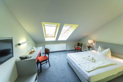 a bedroom with a bed and a desk and a tv at Hotel Rügenblick in Stralsund