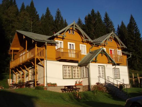 a large wooden house with a balcony on top at Pension Rychta in Hojsova Stráž