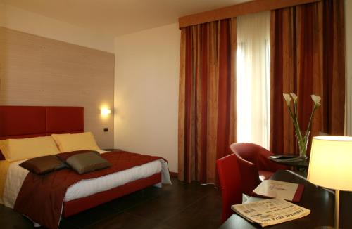 a hotel room with a bed and a chair and a window at Hotel San Clemente in Santarcangelo di Romagna