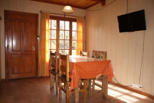 a dining room with a table with chairs and a television at El Puente Aparts- Departamentos Independientes in El Calafate