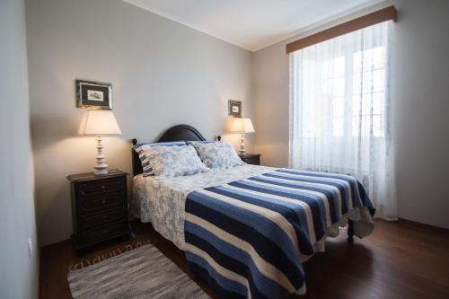 um quarto com uma cama com um cobertor listrado e uma janela em Casa da Avó - Vila do Porto em Vila do Porto