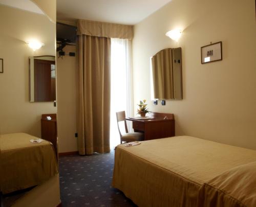 a hotel room with two beds and a desk at Hotel San Clemente in Santarcangelo di Romagna