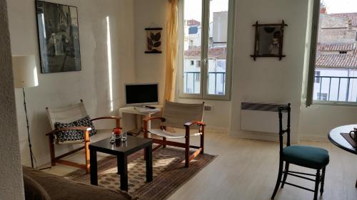 un salon avec un canapé, des chaises et une télévision dans l'établissement Appartement centre historique Beziers, à Béziers