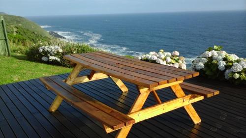 a wooden picnic table sitting on a deck with the ocean at Anglers Paradise in Eersterivierstrand