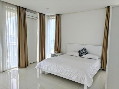 ein weißes Schlafzimmer mit einem großen Bett und Fenstern in der Unterkunft Villa Golf Syariah in Bandung