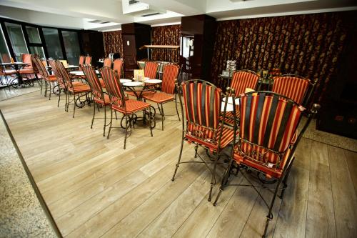una sala da pranzo con tavoli, sedie e uno specchio di LEGENDS CHAMBERS by Grand Pier boutique trade mark location, 4 star rooms with unique historical themes decors with free breakfast only for king rooms and booking stays minim 4 nights a Bucarest
