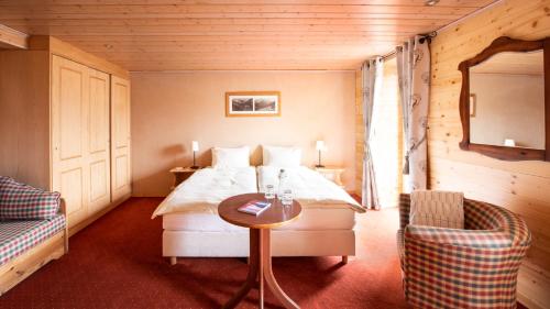 a bedroom with a bed and a table and a chair at Hotel Suisse in Champéry