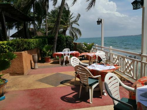 a patio with tables and chairs and the ocean at Hotel Jardin Savana Dakar in Dakar