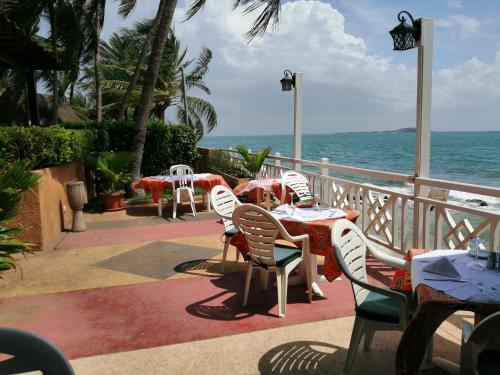 a patio with tables and chairs and the ocean at Hotel Jardin Savana Dakar in Dakar