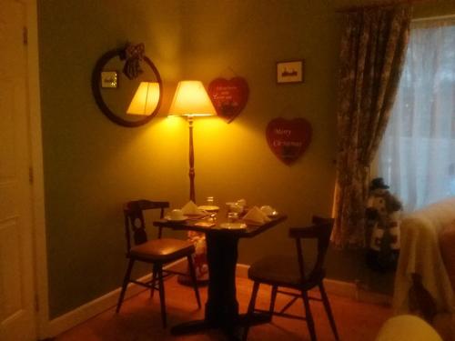 a table with chairs and a lamp in a room at The Meadows Bed and Breakfast in Monaghan