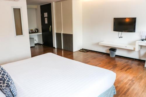 a bedroom with a white bed and a flat screen tv at The Mini R Ratchada in Bangkok