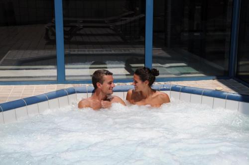 two men in a jacuzzi in a swimming pool at Domaine Naturiste de Riva Bella in Linguizzetta