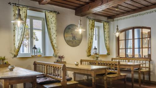a dining room with wooden tables and chairs and windows at Schloss - Schenke Tunzenberg in Mengkofen