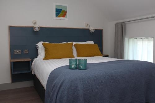 a bedroom with a large bed with two green glasses on it at Baginbun Lodge in Fethard on Sea