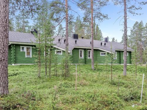 a green house in the woods with trees at Holiday Home Ylläsmukka a 3 by Interhome in Äkäslompolo