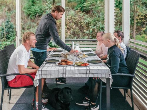 grupa ludzi siedzących przy stole z psem w obiekcie Holiday Home B by Interhome w mieście Porvoo