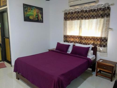 a bedroom with a purple bed and a window at DSK Studio Apartment, Siolim, Goa. in Siolim