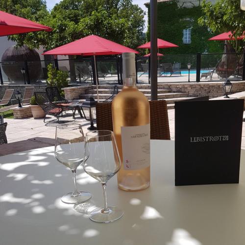 a bottle of wine and two wine glasses on a table at Le Domaine Du Colombier in Malataverne
