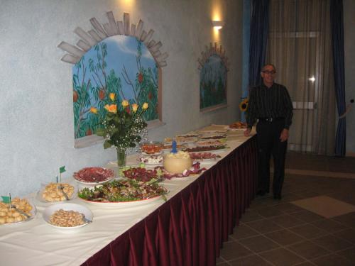 a man standing in front of a long table with food at Hotel Sagittario in San Sperate
