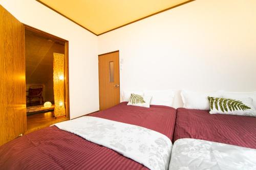 two beds in a bedroom with red and white sheets at Yokkaichi egaosakuie in Shimizucho 1 in Yokkaichi