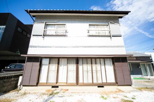 a white building with windows and a balcony at Yokkaichi egaosakuie in Shimizucho 1 in Yokkaichi