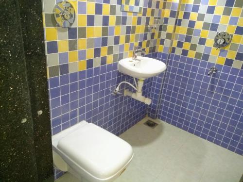 a blue tiled bathroom with a toilet and a sink at DSK Studio Apartment, Siolim, Goa. in Siolim