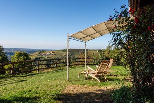 a bench sitting under an umbrella in the grass at Splendido rustico nella Langa in Clavesana