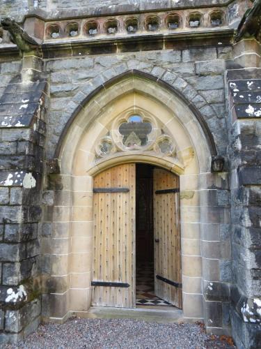 an entrance to a stone building with two wooden doors at Glenwood Apartment at The Highland Club in Fort Augustus