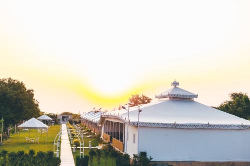 a white building with a white roof and a park at Rawai Luxury Tents Pushkar in Pushkar