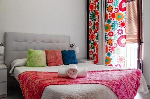 a bed with a pink blanket and colorful pillows at Nest Style Granada in Granada