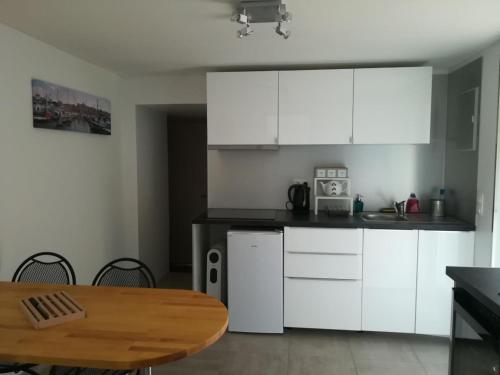 une cuisine avec des armoires blanches et une table en bois dans l'établissement Appartement Villa Marcel Cottreau, à Marseille